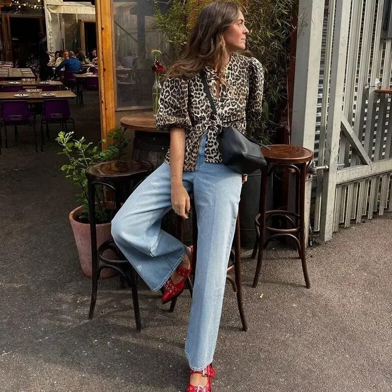 Leopardenmuster-Top für Damen im Outdoor-Look mit Schlagjeans und roten Schuhen – stilvolles Leoparden-Top Damenoberteil.
