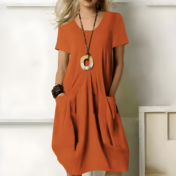  Leuchtend oranges locker sitzendes Kleid mit breitem Gürtel und kurzen Ärmeln, getragen von einer Frau in sanft beleuchtetem Raum
