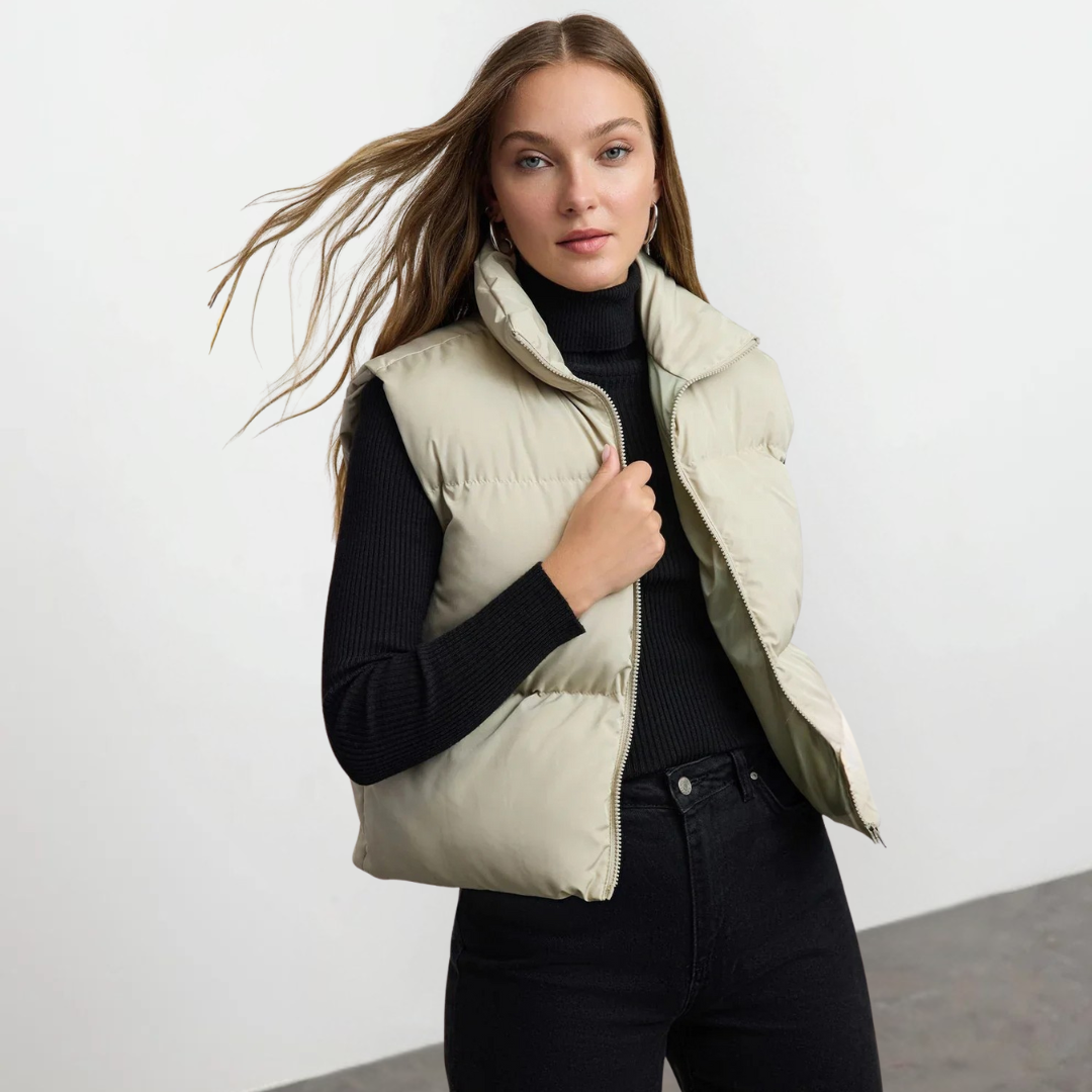 Steppweste in Beige mit Reißverschlussfront, hohem Kragen und leichter Polsterung für Damen.